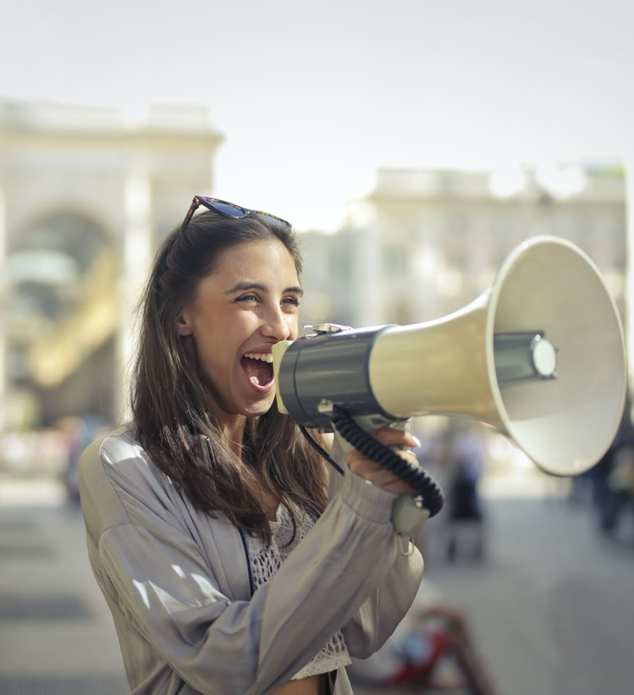 Cheerful young woman screaming into megaphone